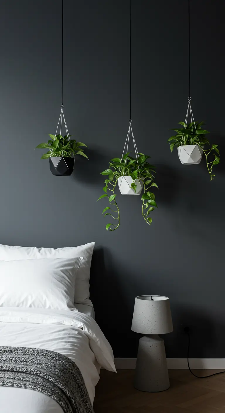 Trois pots suspendus géométriques en noir et blanc contre un mur anthracite, au-dessus d'une table de nuit.
