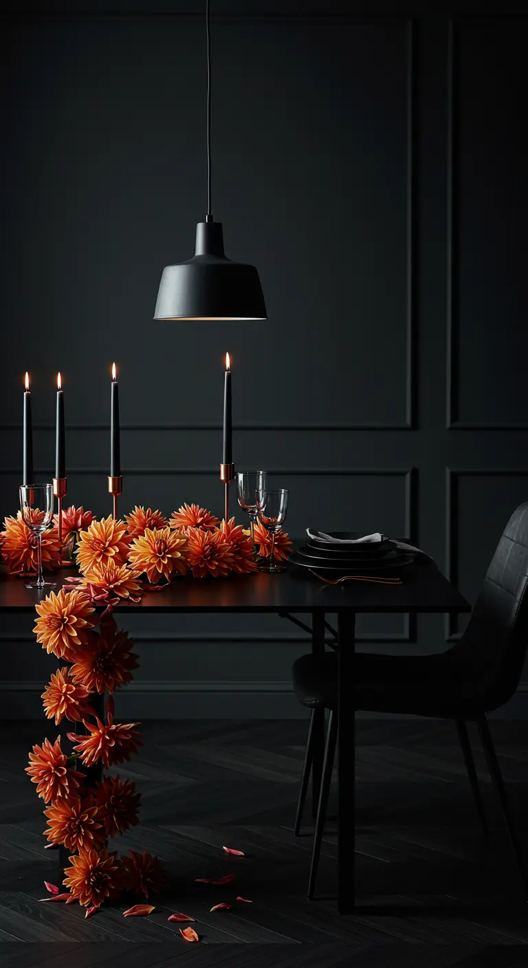 Table de dîner noire dans une pièce sombre, avec une guirlande de dahlias orange vif.