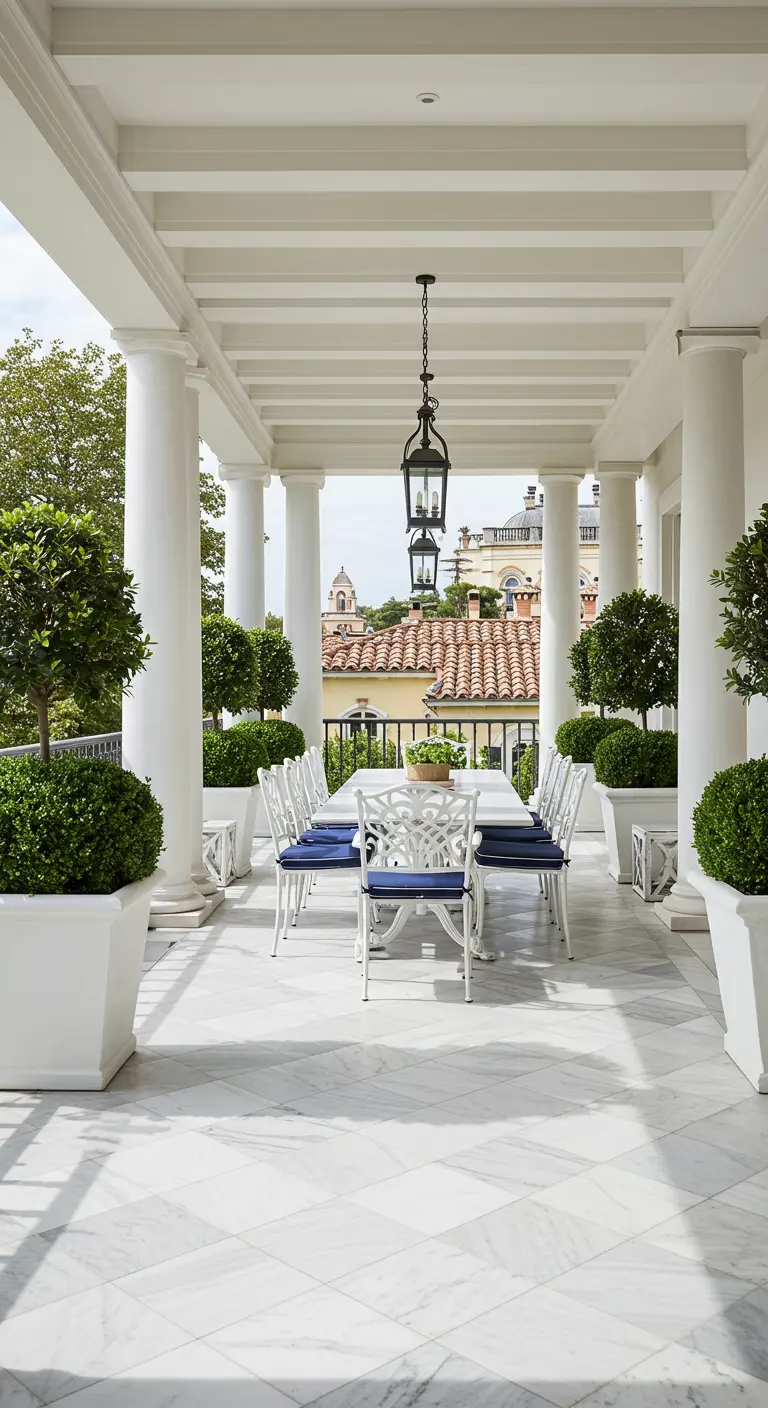 Salle à manger extérieure sous une colonnade blanche, avec des chaises à assises bleu marine.