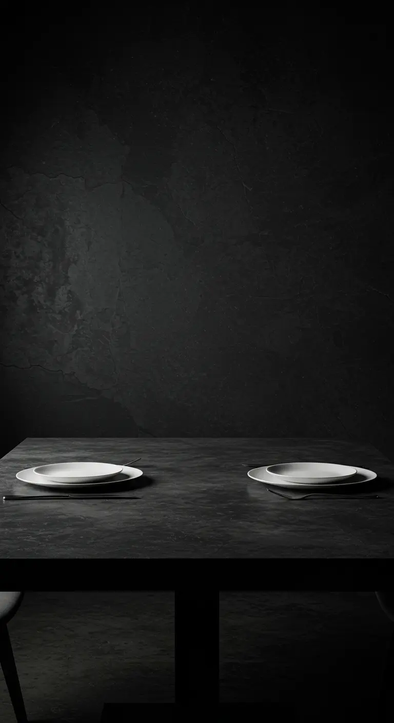Table noire minimaliste avec seulement deux assiettes blanches dressées face à face.