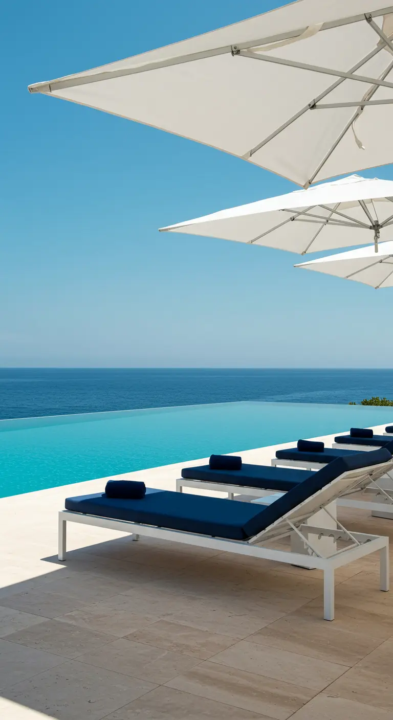 Transats blancs minimalistes avec matelas bleu marine au bord d'une piscine à débordement.