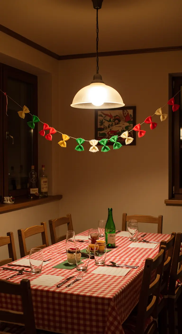 Guirlande de pâtes farfalle peintes en rouge, vert et jaune au-dessus d'une table à nappe à carreaux.