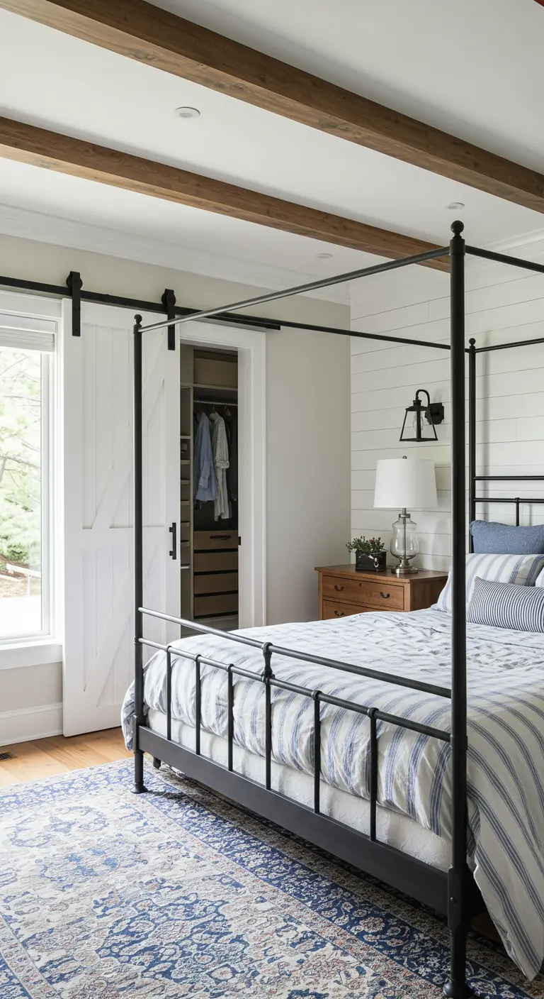 Chambre de style farmhouse avec un lit à baldaquin noir et une porte de grange coulissante.